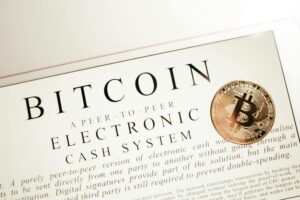 Image depicting Bitcoin electronic cash system with a physical Bitcoin coin prominently displayed.